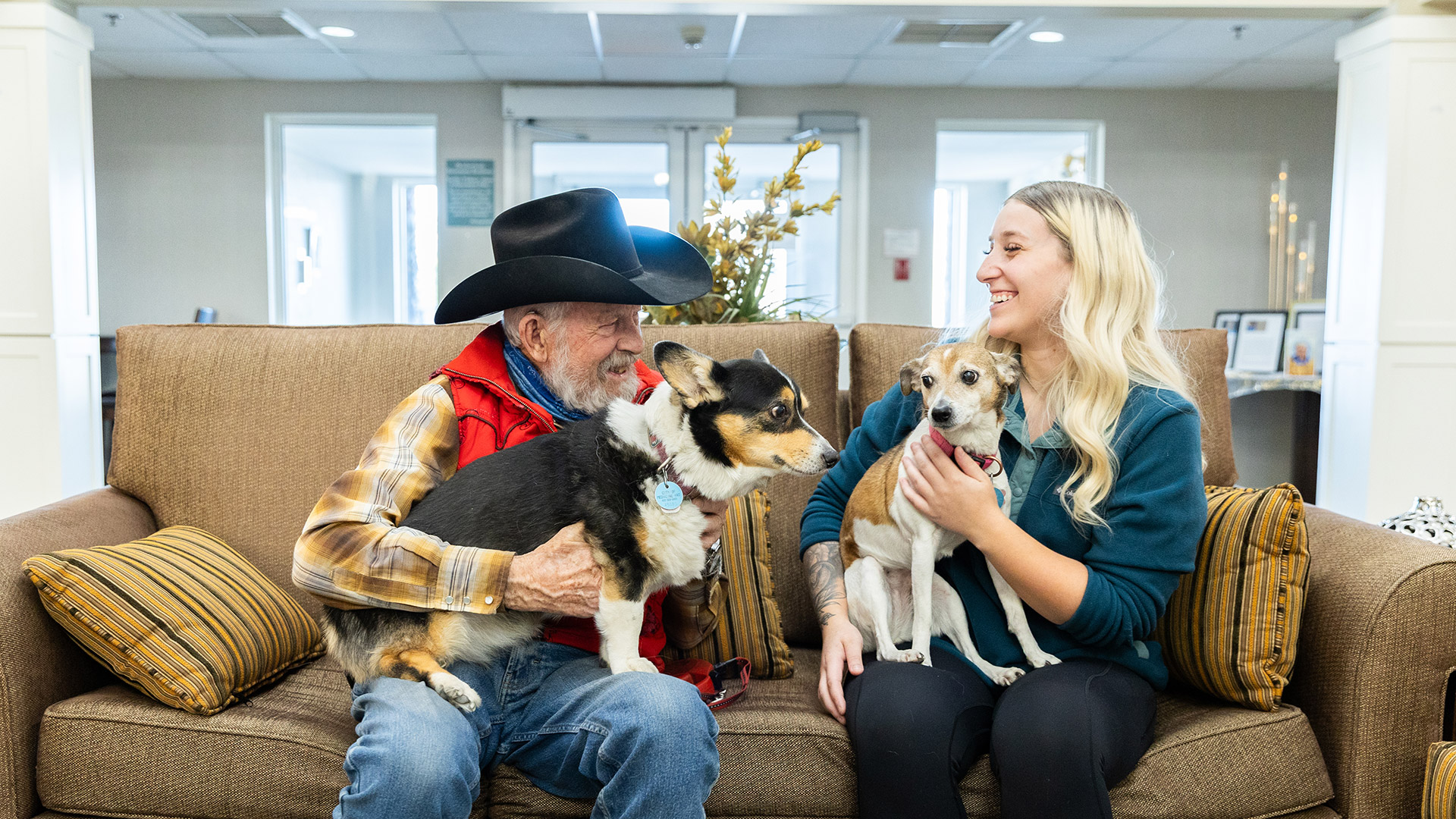 resident and staff sitting on sofa with dogs