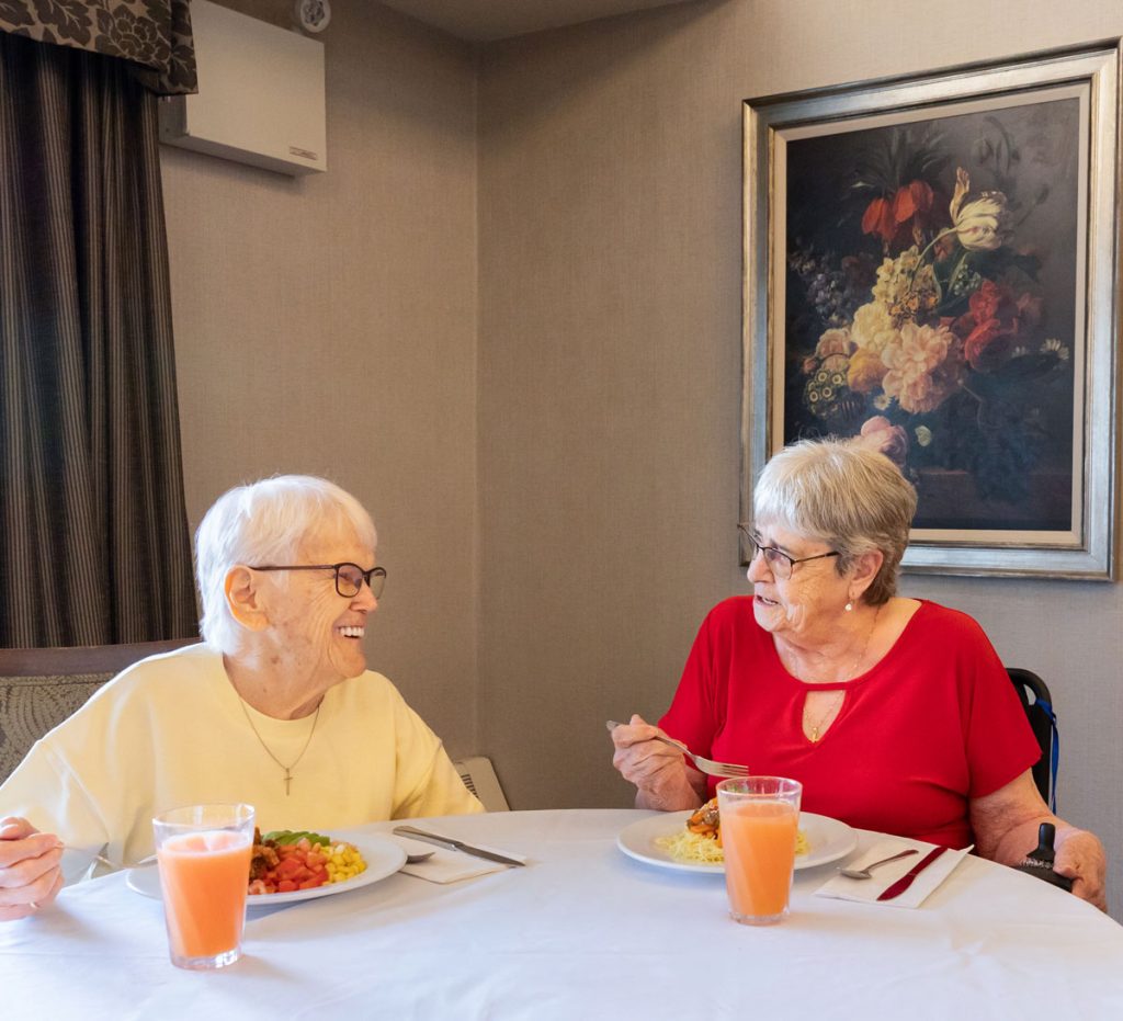 two smiling residents eating